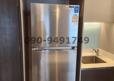 Modern stainless steel refrigerator in a small kitchen with wooden cabinets