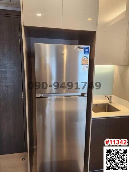 Modern stainless steel refrigerator in a small kitchen with wooden cabinets