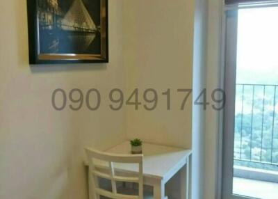 Cosy dining area with a simple white table and chairs, framed picture on the wall, and a window offering natural light