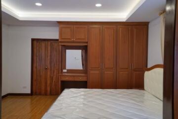 Spacious bedroom with wooden wardrobe and hardwood floors