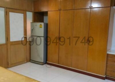 Spacious bedroom with large wardrobe and refrigerator