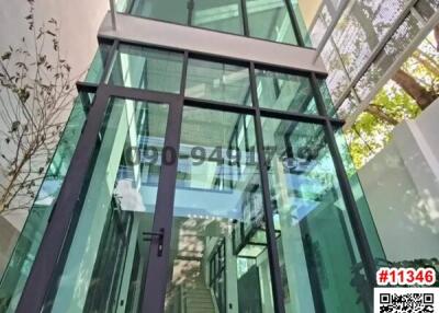 Modern glass building exterior with transparent walkway and lush greenery