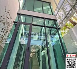 Modern glass building exterior with transparent walkway and lush greenery