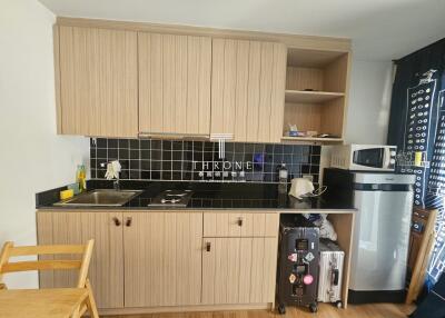 Compact modern kitchen with wooden cabinetry and black countertops