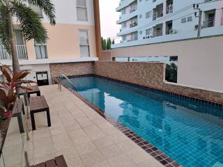 Swimming pool area with surrounding building and palm trees