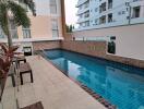 Swimming pool area with surrounding building and palm trees