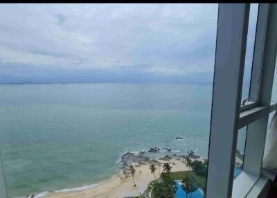 Stunning coastal view from a high-rise building, featuring a clear ocean view with a beach and lush greenery