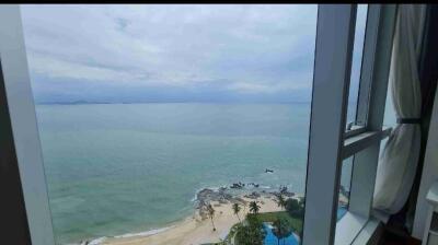 Stunning coastal view from a high-rise building, featuring a clear ocean view with a beach and lush greenery