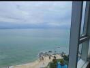 Stunning coastal view from a high-rise building, featuring a clear ocean view with a beach and lush greenery