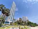 High-rise residential building with landscaped garden under clear blue skies