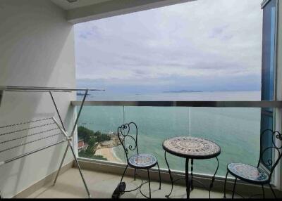 Cozy balcony with ocean view, featuring a seating area and drying rack