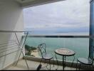 Cozy balcony with ocean view, featuring a seating area and drying rack