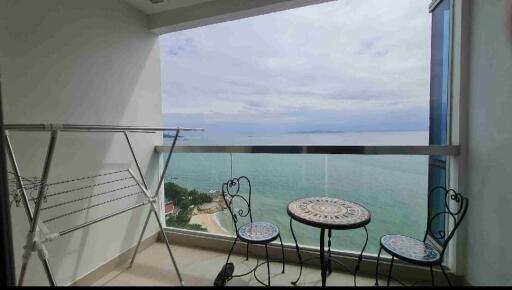 Cozy balcony with ocean view, featuring a seating area and drying rack