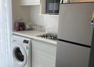 Compact modern kitchen with washing machine and stainless steel refrigerator