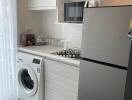 Compact modern kitchen with washing machine and stainless steel refrigerator