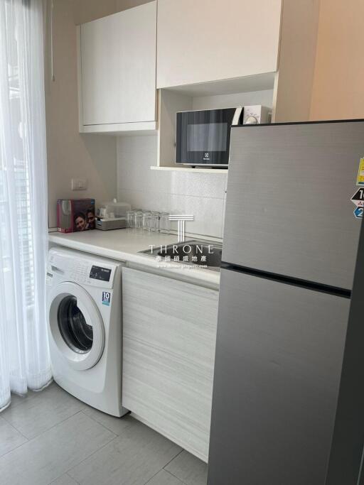 Compact modern kitchen with washing machine and stainless steel refrigerator