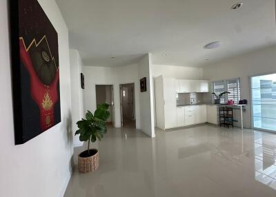Spacious interior of a modern building with open-plan living area, kitchen, and glossy tiled flooring