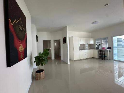 Spacious interior of a modern building with open-plan living area, kitchen, and glossy tiled flooring