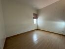 Empty bedroom with wooden flooring and a single window