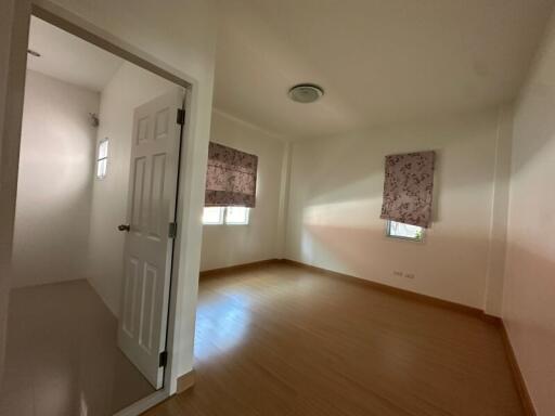 Empty bedroom with hardwood floors and natural light