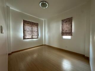 Empty bedroom with hardwood floors and two windows with closed patterned blinds