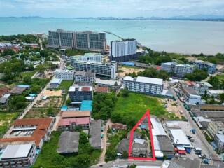 Aerial view of a residential building complex near the coastline with marked property area