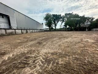 Empty land with tire tracks adjacent to industrial buildings