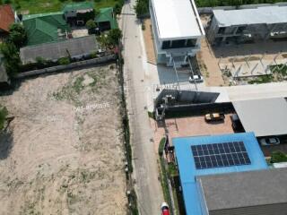 Aerial view of a vacant land plot next to urban road with nearby buildings