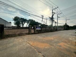 Residential street view with entrance gate and surrounding fence