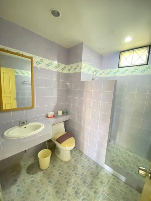 A well-lit bathroom with purple tiles and shower section