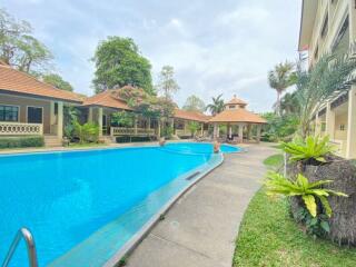 Spacious outdoor swimming pool area with trees and adjacent residential buildings