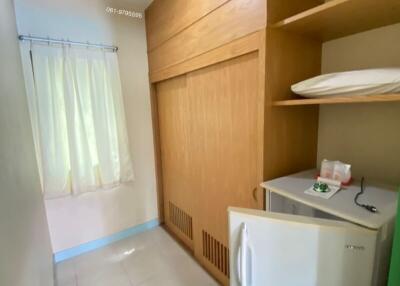 Compact building utility area with wooden storage, washing machine and tiled floor