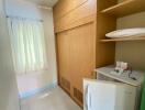 Compact building utility area with wooden storage, washing machine and tiled floor