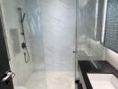 Modern bathroom with glass shower enclosure and white marble walls
