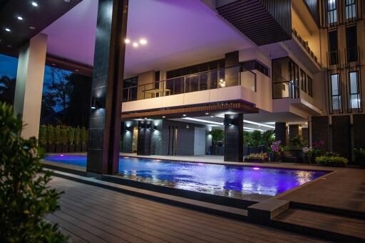 Modern house exterior at dusk with illuminated swimming pool
