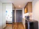Compact studio apartment with integrated living space featuring kitchenette, bedroom area, and mirrored wardrobe