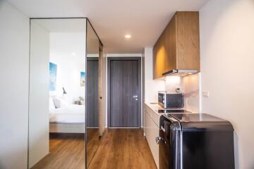Compact studio apartment with integrated living space featuring kitchenette, bedroom area, and mirrored wardrobe