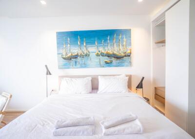 Bright and airy bedroom with a large painting above the bed