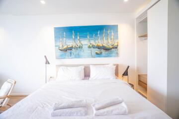 Bright and airy bedroom with a large painting above the bed