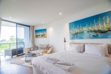 Bright and airy bedroom with a large painting over the bed and balcony access