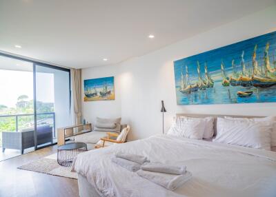 Bright and airy bedroom with a large painting over the bed and balcony access
