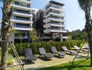 Modern apartment building with outdoor relaxation space featuring lounge chairs and landscaped garden