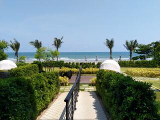Oceanfront view with green lawn and path leading to the beach