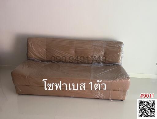 New sofa wrapped in plastic in an empty living room