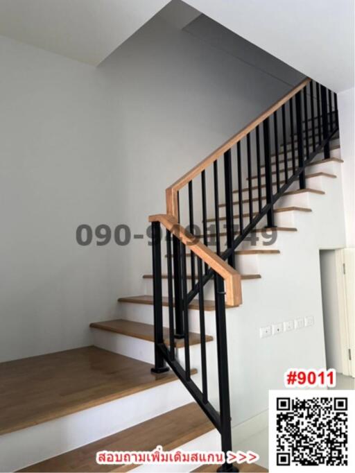 Modern staircase with wooden steps and black metal railing in a house