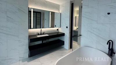 Modern bathroom with marble walls, double vanity, and walk-in shower