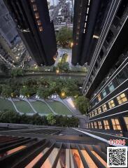 Aerial view of residential building complex gardens and amenities, with surrounding cityscape at dusk