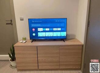 Modern living room with a large television and wooden cabinet