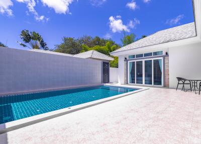 Bright outdoor pool area with a clear blue sky and sliding glass doors leading to the interior