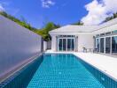Bright and modern outdoor pool area with adjacent house and clear blue sky